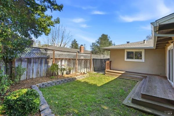 a view of a backyard with table and chairs potted plants and wooden fence