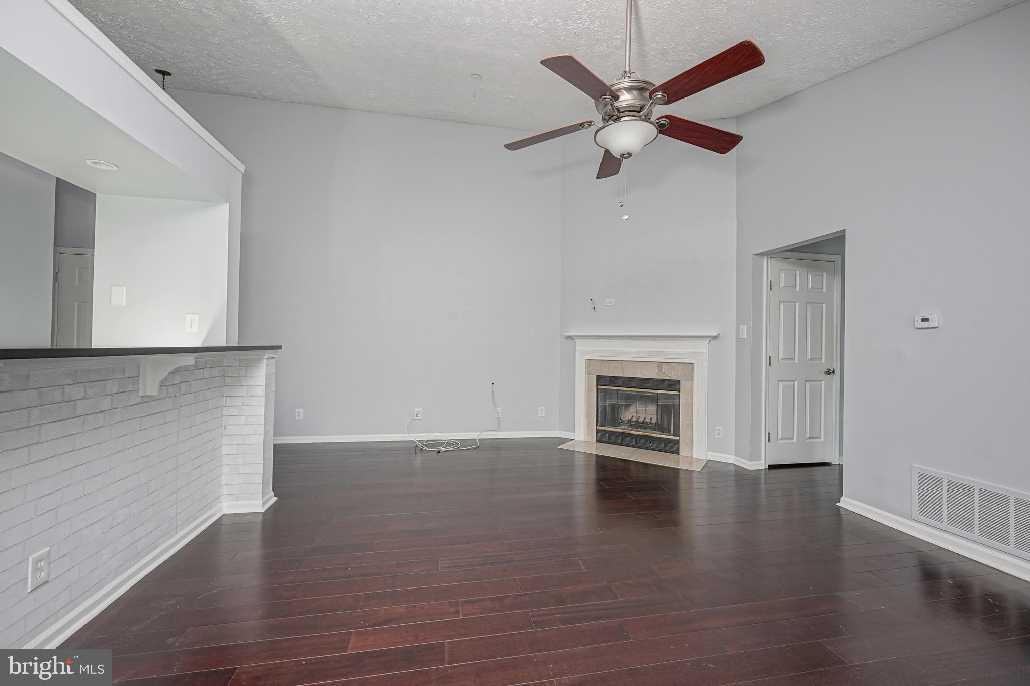 84 Eldon Way Marlton, NJ 08053 - Photo 6 of 27 an empty room with wooden floor a ceiling fan a fireplace and windows