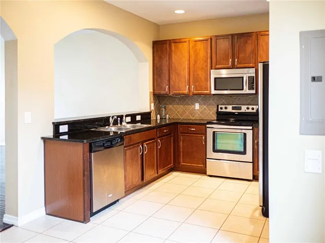 a kitchen with stainless steel appliances granite countertop a stove a sink and a refrigerator