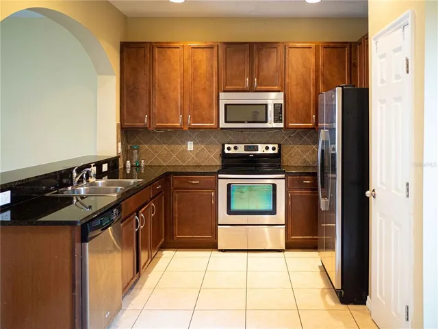 a kitchen with stainless steel appliances granite countertop a stove a sink and a microwave