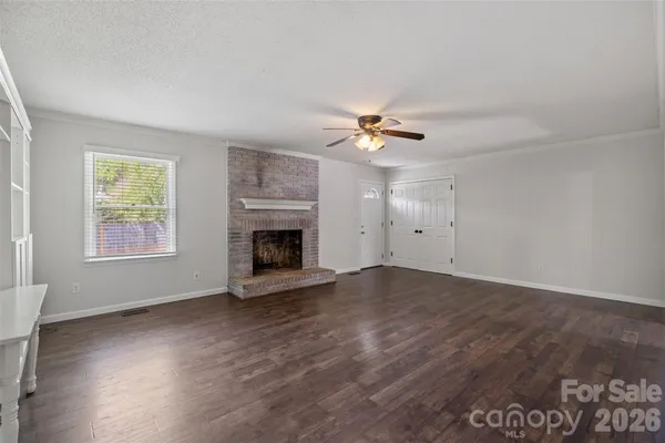 an empty room with windows and fireplace