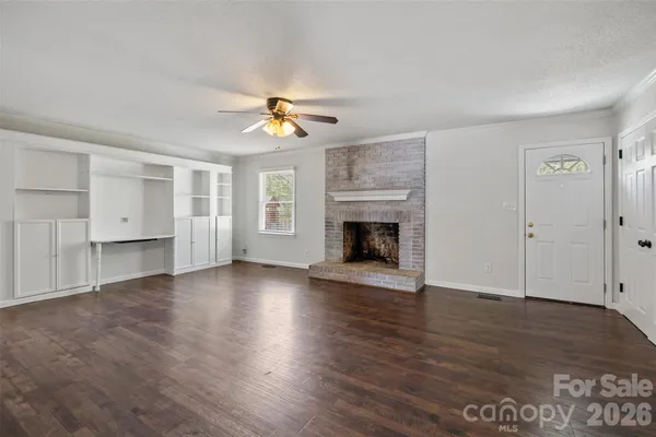 an empty room with wooden floor fireplace and window