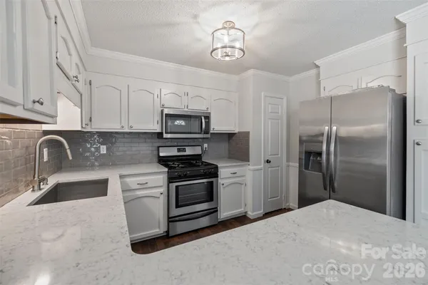 a kitchen with stainless steel appliances granite countertop a refrigerator a stove a sink and a microwave