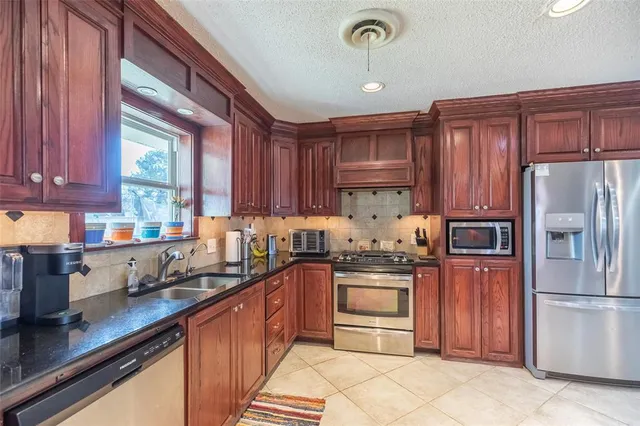 a kitchen with stainless steel appliances granite countertop a refrigerator stove a sink and dishwasher
