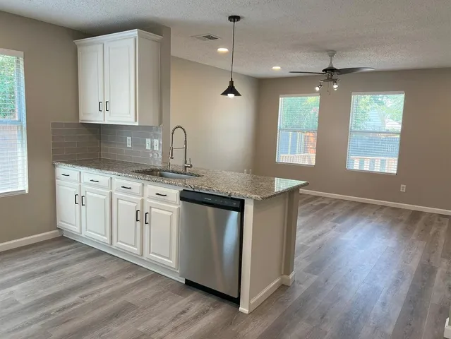 a kitchen with stainless steel appliances granite countertop a sink cabinets and wooden floor