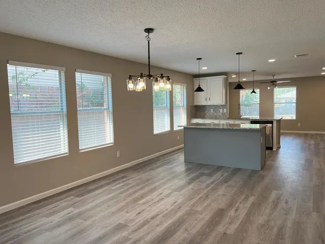 a living room with kitchen island granite countertop wooden floor stainless steel appliances and a window