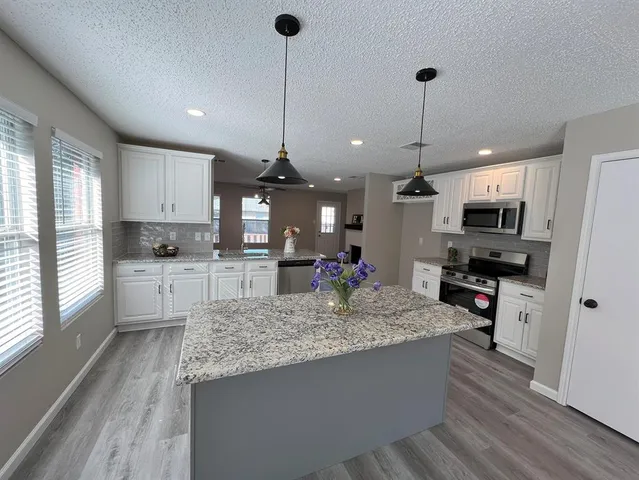 a kitchen with stainless steel appliances granite countertop a sink refrigerator and microwave