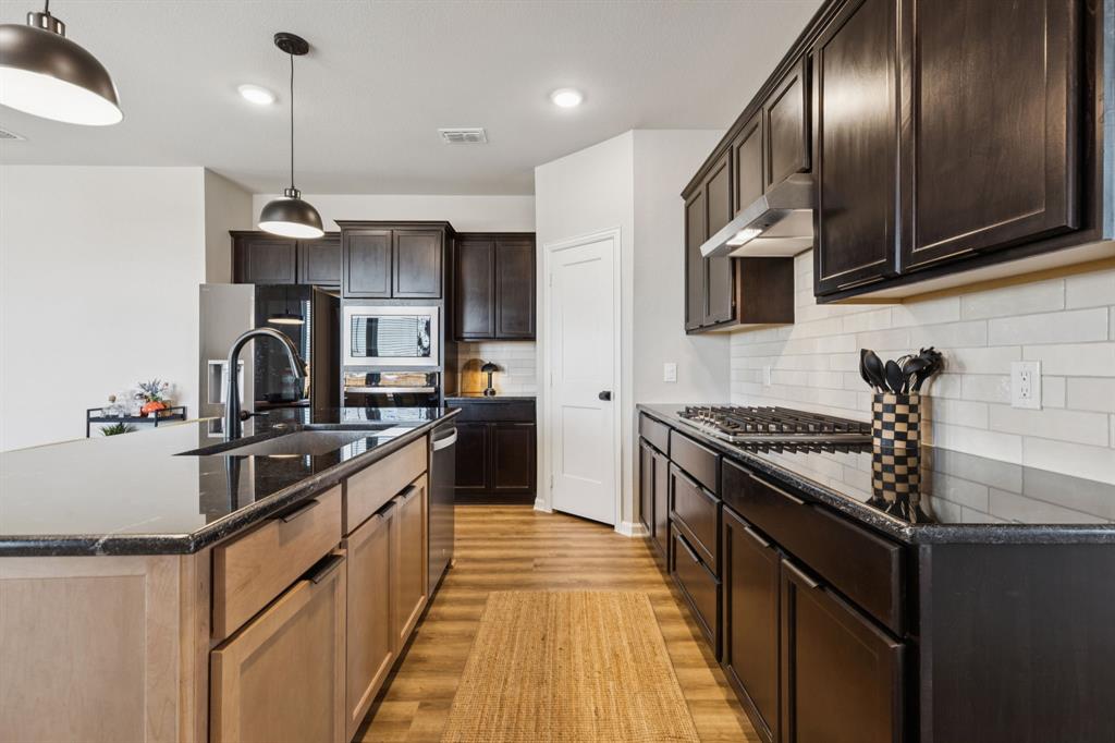490 Tender Summit Lavon, TX 75166 - Photo 5 of 23 a kitchen with granite countertop stainless steel appliances and wooden floor