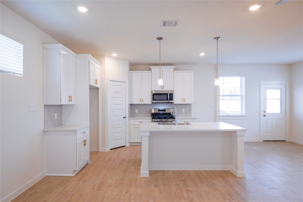 6618 Escondido Drive Rosharon, TX 77583 - Photo 13 of 31 a kitchen with stainless steel appliances a refrigerator a sink dishwasher a stove and white cabinets with wooden floor