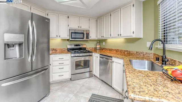 a kitchen with stainless steel appliances granite countertop a refrigerator sink and stove