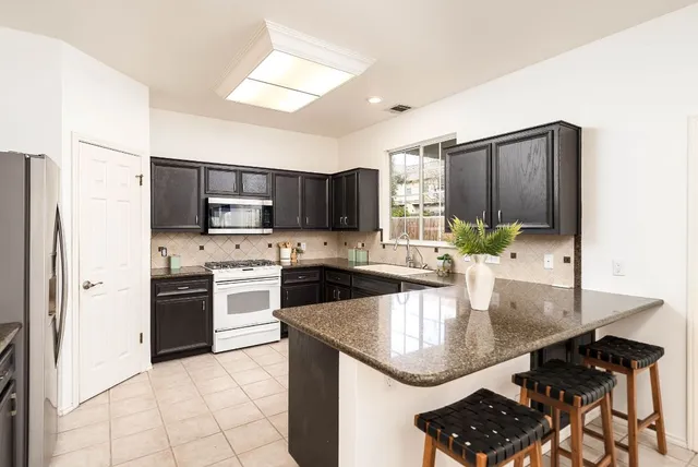 a kitchen with stainless steel appliances granite countertop a sink a stove and refrigerator