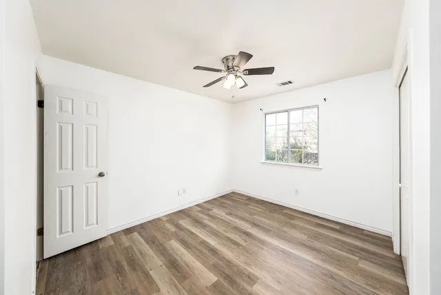 an empty room with windows and fan