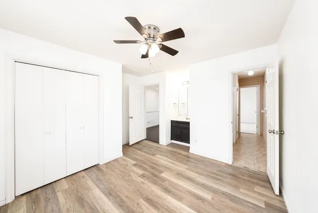a view of empty room with wooden floor and fan