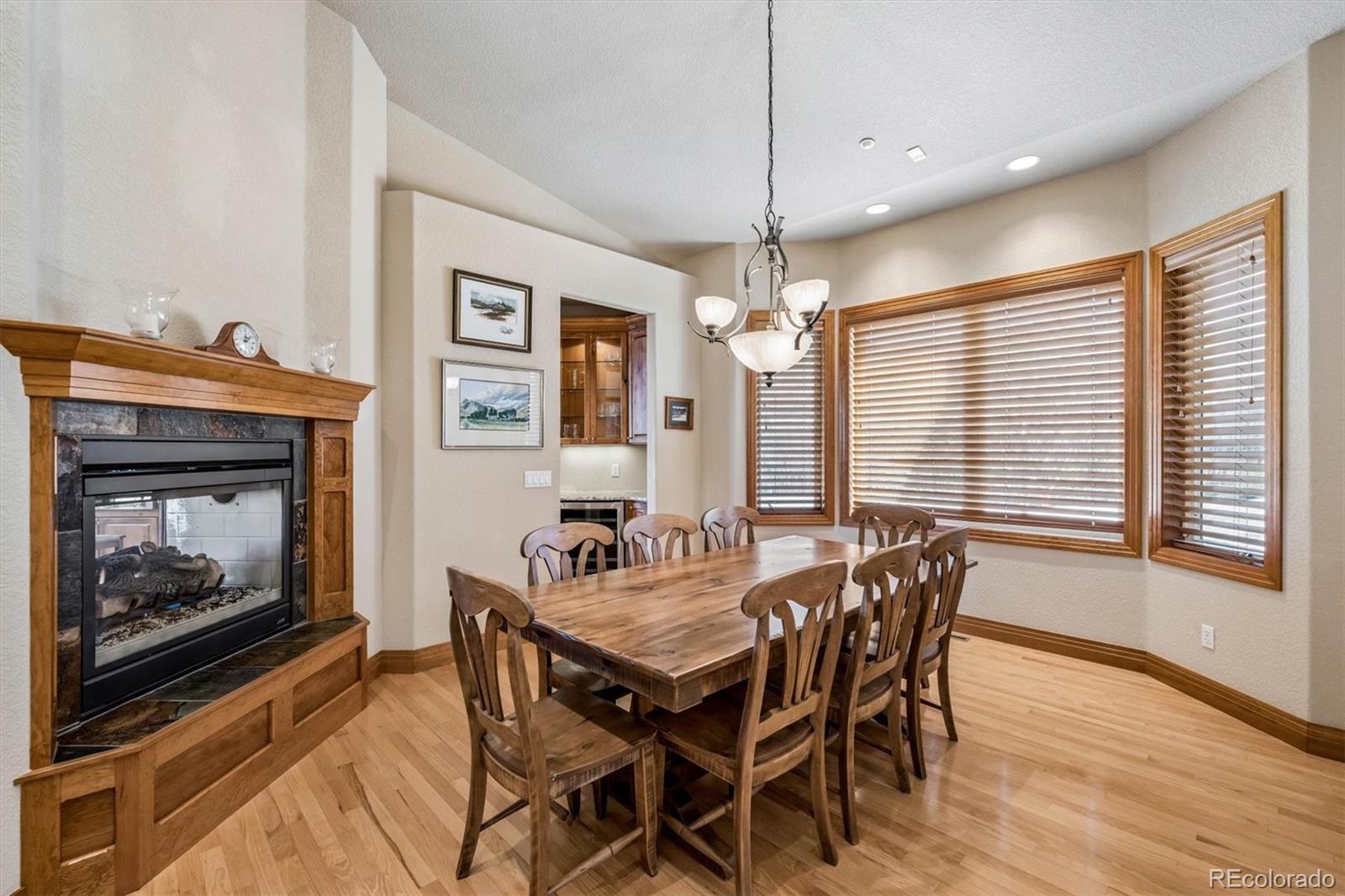 3959 Serenade Road Castle Rock, CO 80104 - Photo 22 of 50 a dining room with wooden floor a chandelier a wooden table and chairs