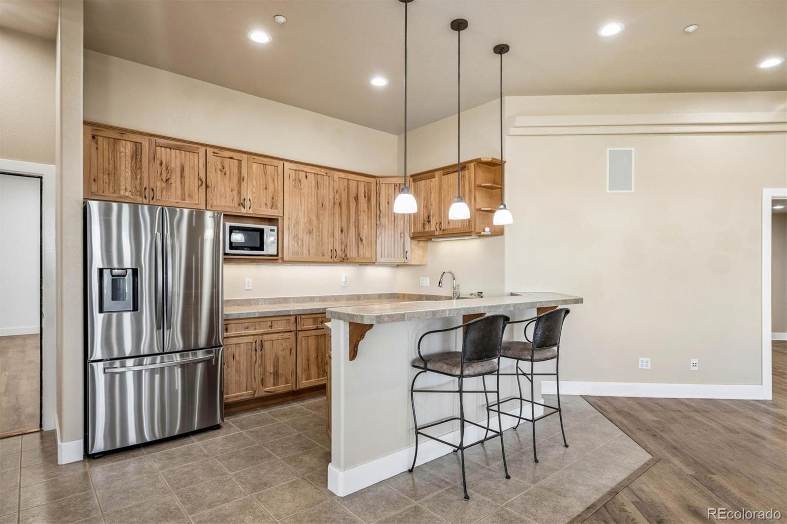 3959 Serenade Road Castle Rock, CO 80104 - Photo 40 of 50 a kitchen with stainless steel appliances granite countertop a sink a stove a refrigerator and island with wooden floor