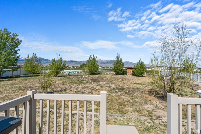 444 South Saddle Road Grantsville, UT 84029 - Photo 23 of 33 Expansive backyard featuring a white perimeter fence, mature trees, a storage shed, and distant mountain scenery
