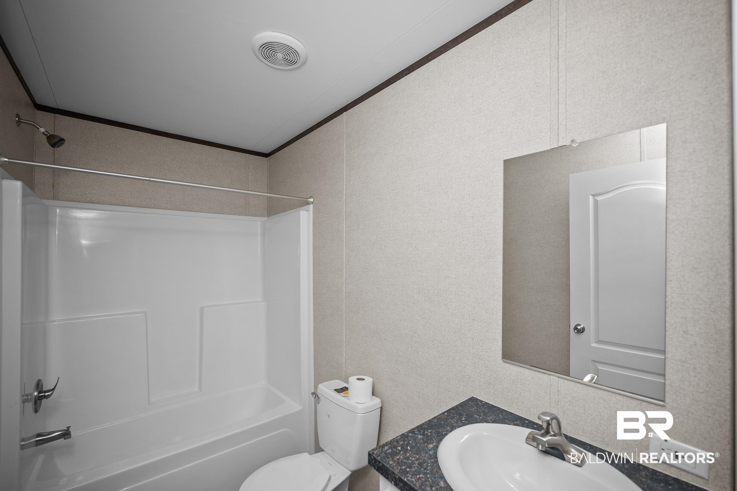 21601 Westside Loop Silverhill, AL 36576 - Photo 31 of 42 Bathroom featuring a white bathtub/shower combination, white toilet, and a vanity with a dark speckled countertop and an undermount sink