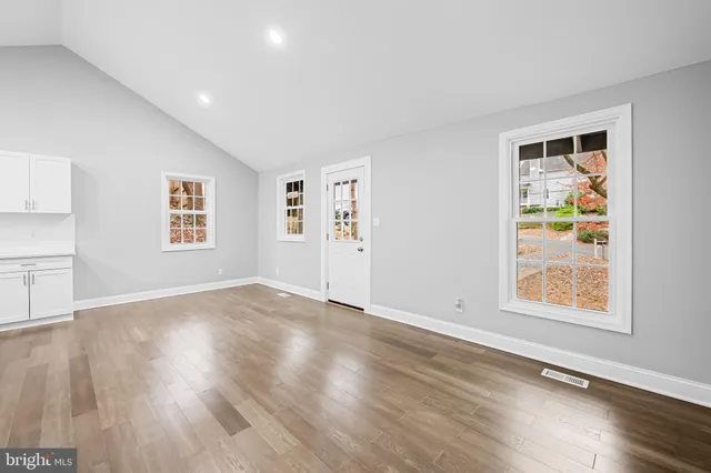 a view of an empty room with a window and wooden floor