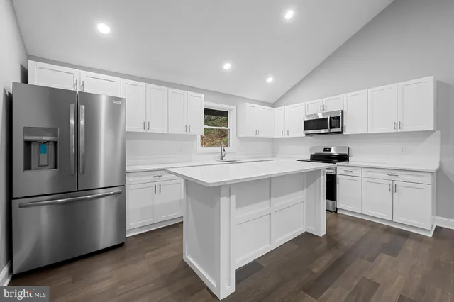 a kitchen with white cabinets stainless steel appliances and wooden floor