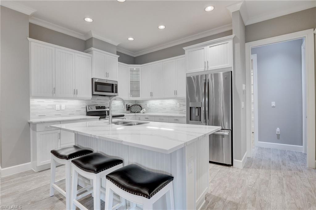 5708 Highbourne Drive Naples, FL 34113 - Photo 8 of 28 a kitchen with a sink a stove a refrigerator and white cabinets