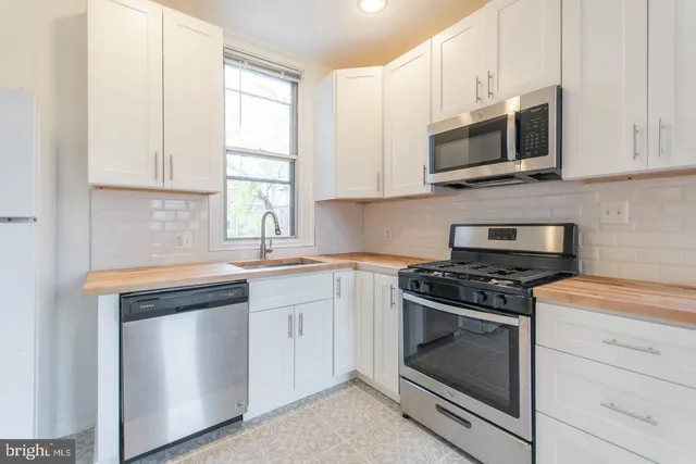 a kitchen with stainless steel appliances granite countertop white cabinets a sink and a stove