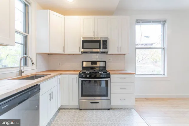 a kitchen with stainless steel appliances granite countertop white cabinets and a stove