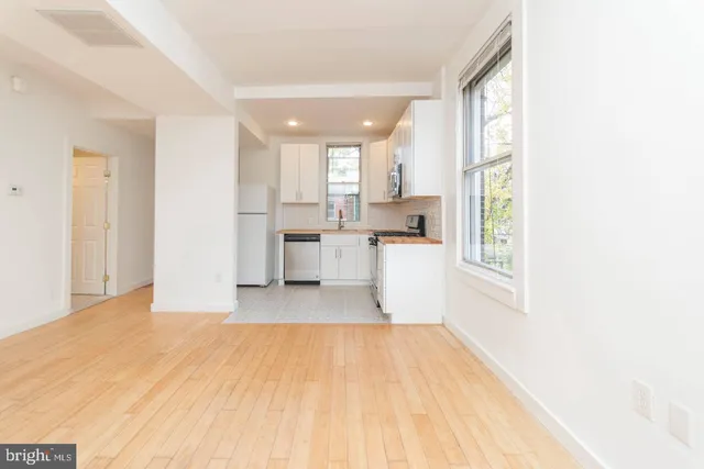 a view of a kitchen with wooden floor and a living room