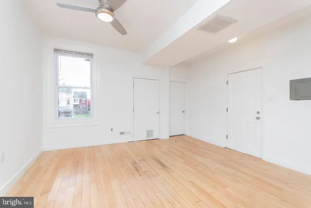 a view of empty room with wooden floor and fan