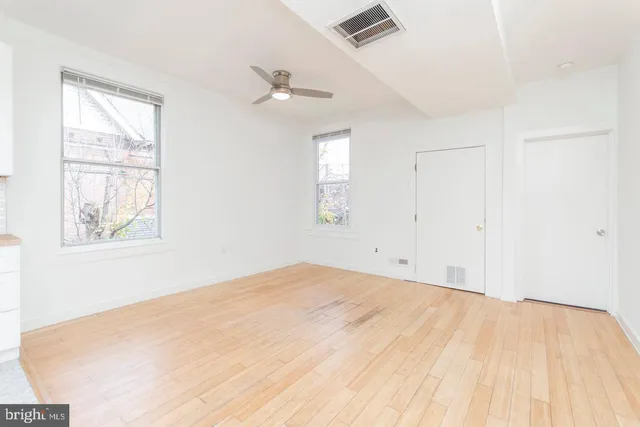 a view of empty room with wooden floor and fan