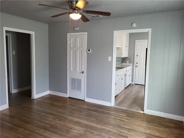 an empty room with wooden floor and a ceiling fan