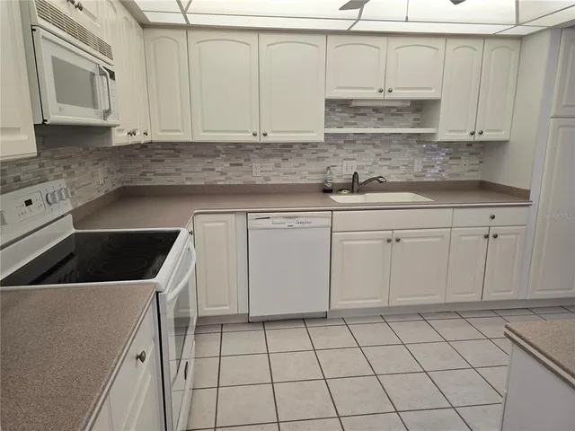 a kitchen with white cabinets a sink and a stove