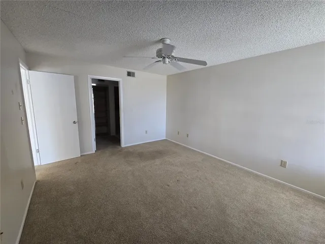 a view of a room with a ceiling fan and carpet