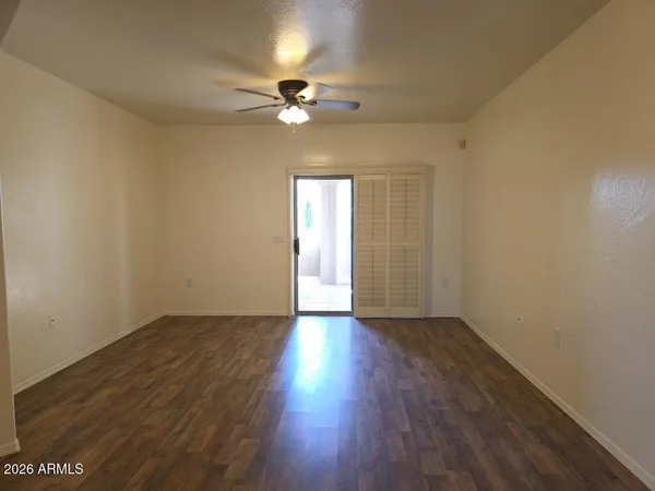 a view of an empty room with wooden floor and a window
