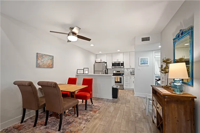 a kitchen with stainless steel appliances kitchen island granite countertop a dining table chairs and a refrigerator