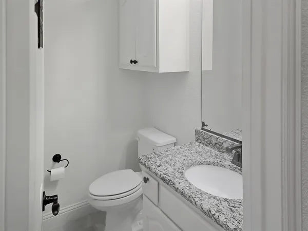 a bathroom with a granite countertop sink and a toilet