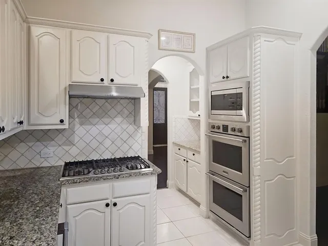 a kitchen with stainless steel appliances granite countertop a stove a microwave and a refrigerator