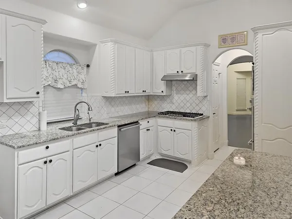 a kitchen with granite countertop white cabinets and white appliances