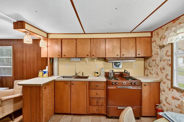 a room with stainless steel appliances wooden cabinets and a bed
