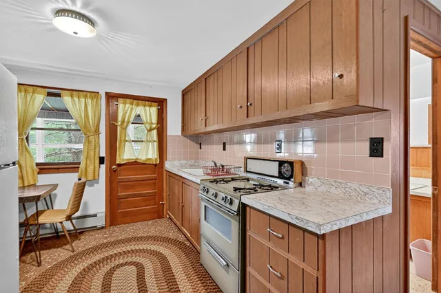 a kitchen with a stove a sink dishwasher and wooden cabinets with a large window