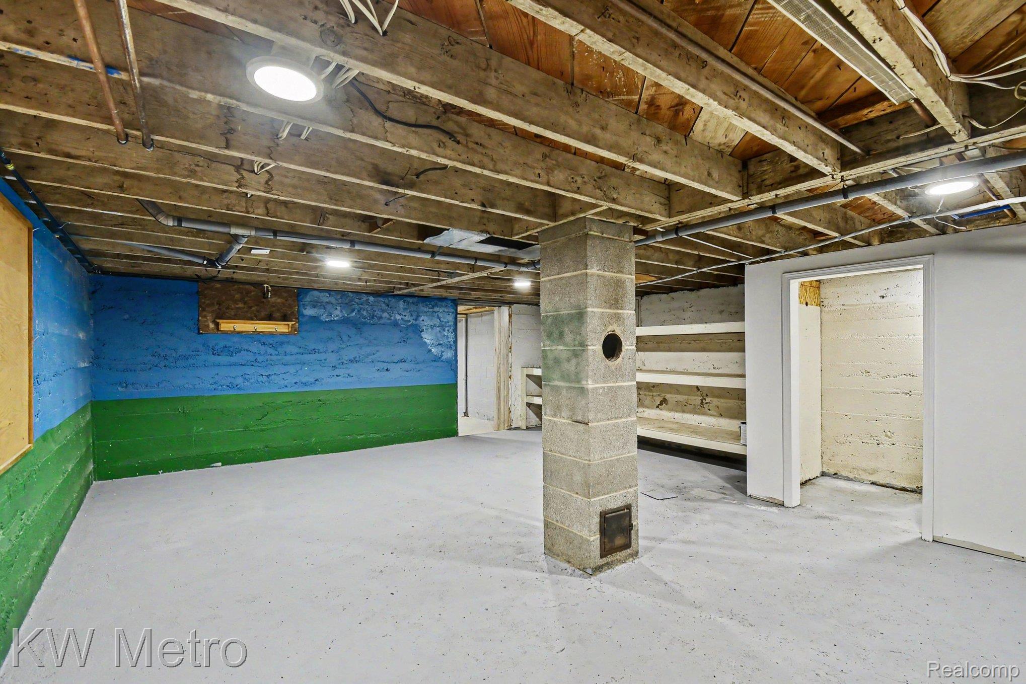 2682 East Haskell Lake Road Harrison, MI 48625 - Photo 34 of 61 Spacious utility room featuring an exposed joist ceiling, concrete block support pillar, painted concrete walls, and durable concrete flooring