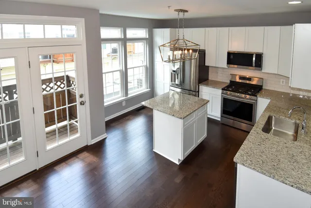 a kitchen with stainless steel appliances wooden floor and a refrigerator
