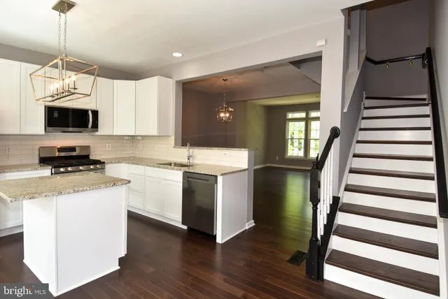a kitchen with a sink and a stove top oven with wooden floor