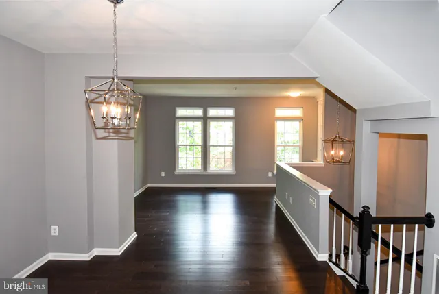 a view of a hallway with wooden floor and stairs