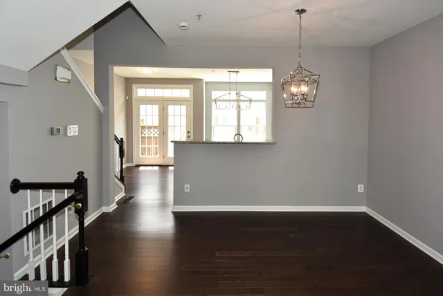 a view of a room with wooden floor chandelier and windows