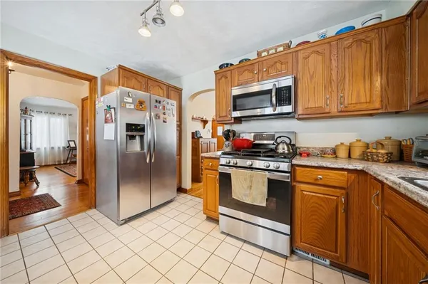 a kitchen with stainless steel appliances granite countertop a refrigerator a stove top oven and sink