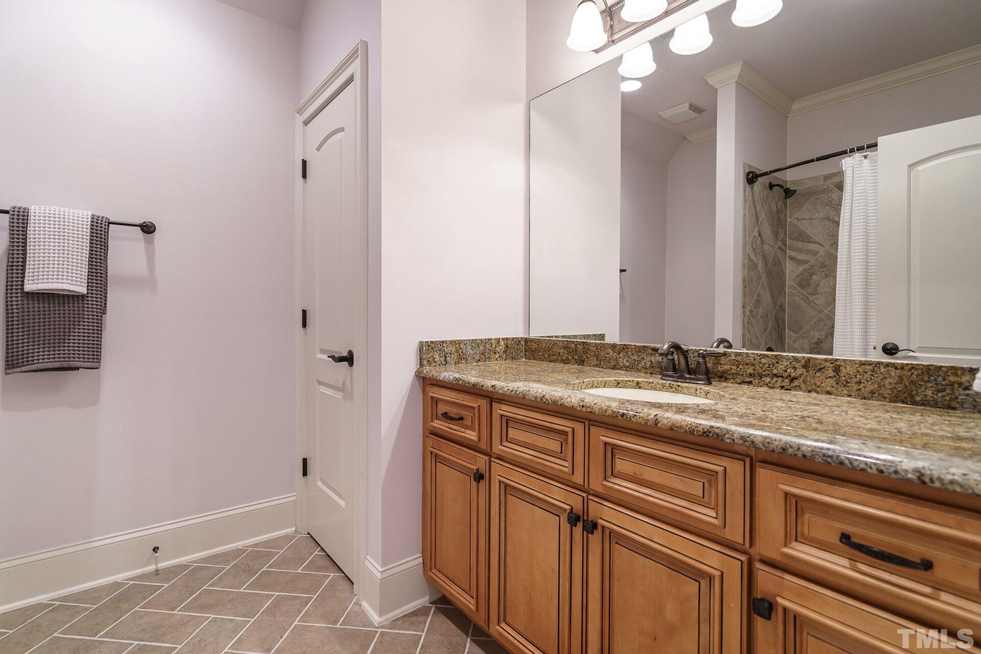 8313 Rue Cassini Court Raleigh, NC 27615 - Photo 31 of 74 a bathroom with a granite countertop sink and a mirror