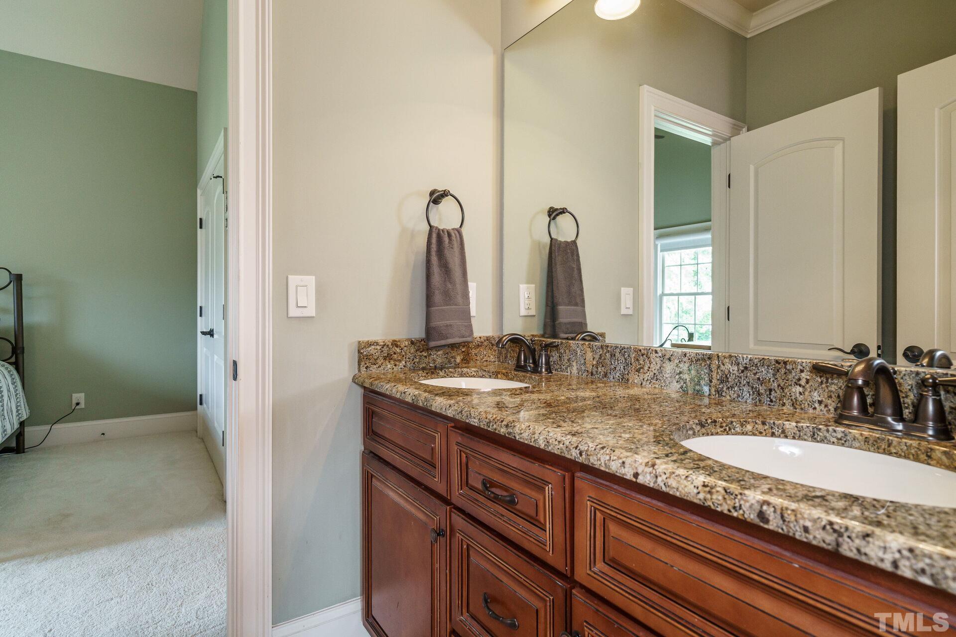8313 Rue Cassini Court Raleigh, NC 27615 - Photo 34 of 74 a bathroom with a granite countertop sink and a mirror