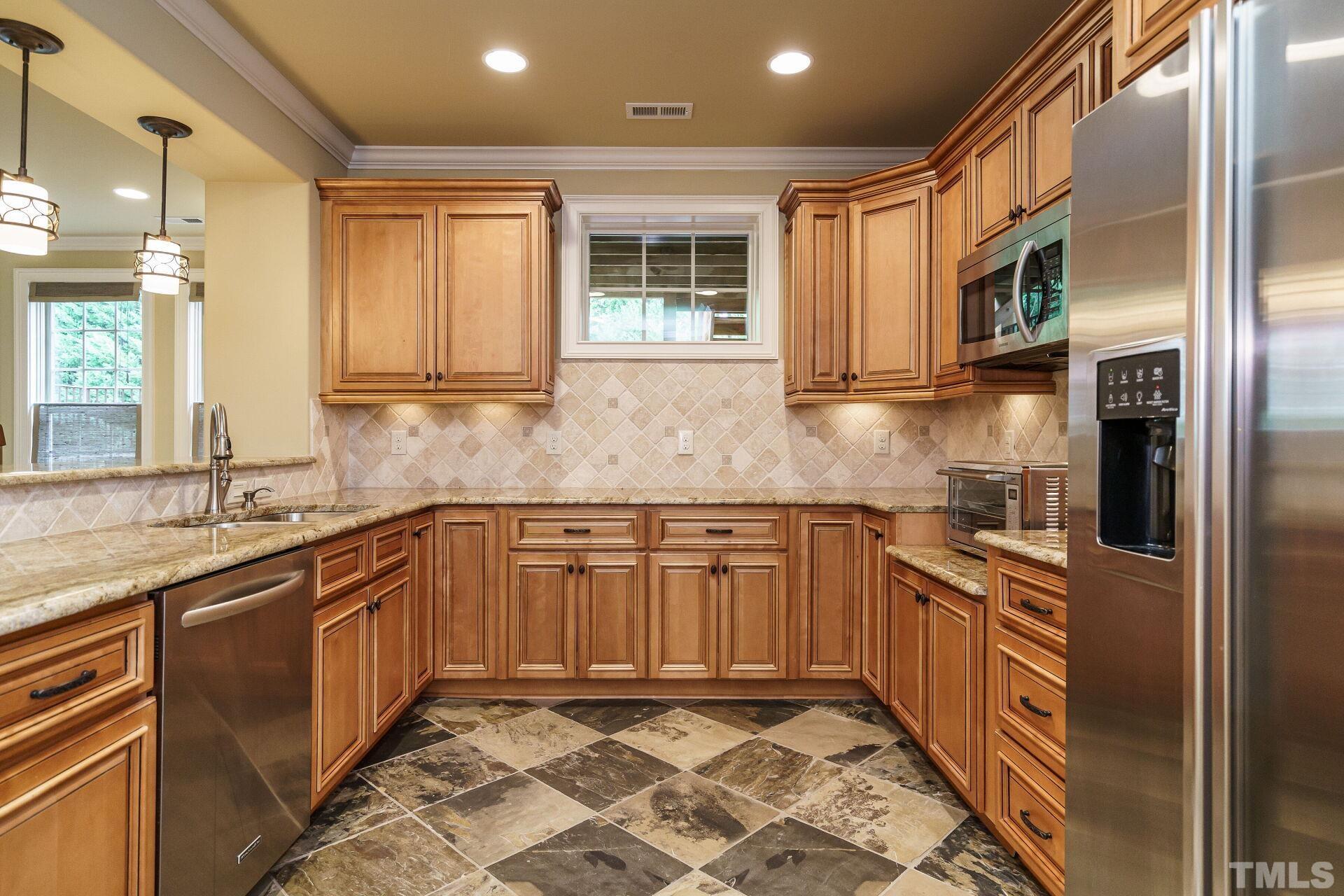 8313 Rue Cassini Court Raleigh, NC 27615 - Photo 46 of 74 a kitchen with stainless steel appliances granite countertop a sink stove and refrigerator
