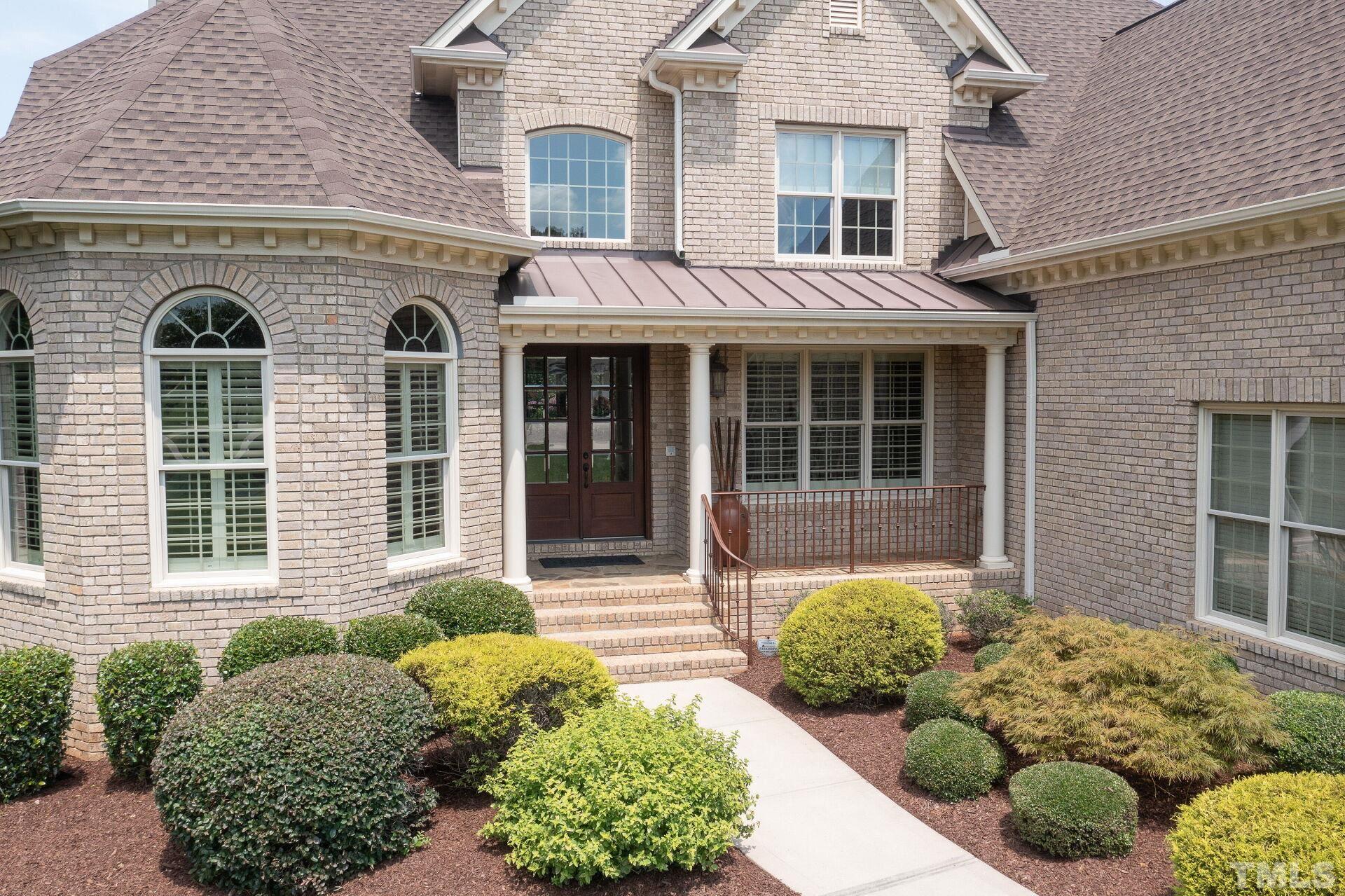 8313 Rue Cassini Court Raleigh, NC 27615 - Photo 6 of 74 front view of a brick house with a large window and potted plants