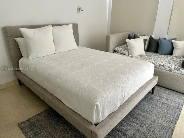 a large white bed in a bedroom next to a couch